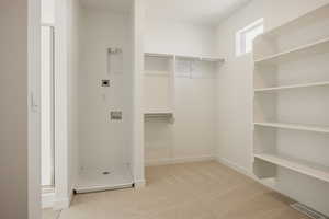 Walk in closet featuring light colored carpet