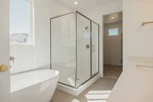 Bathroom with a stall shower, a soaking tub, light tile patterned floors, and vanity
