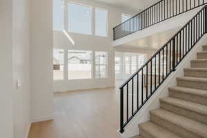 Stairway featuring healthy amount of natural light, a high ceiling, and wood finished floors