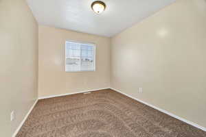 Carpeted spare room featuring baseboards and a textured ceiling