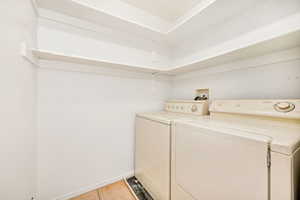 Washroom with independent washer and dryer and light tile patterned floors