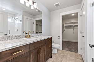 Bathroom with a spacious closet, vanity, a shower stall, and light tile patterned floors