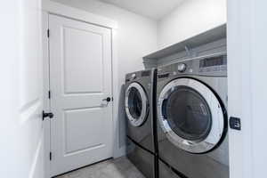Laundry area with independent washer and dryer and light tile patterned flooring
