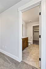 Bathroom featuring vanity, light tile patterned floors, and a spacious closet