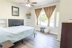 Bedroom featuring light wood-style flooring, a fireplace, and ceiling fan