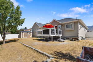 Rear view of house featuring a deck, a fenced backyard, a shed, roof with shingles, and stucco siding