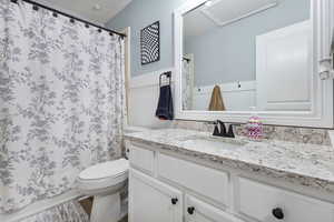 Bathroom featuring vanity, a shower with shower curtain, and wainscoting