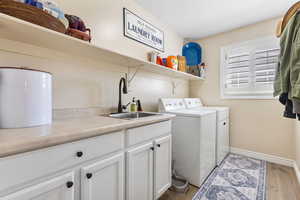 Laundry room featuring light wood-style flooring, washing machine and clothes dryer, and cabinet space