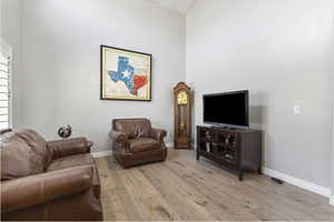 Living area with light wood finished floors and a towering ceiling
