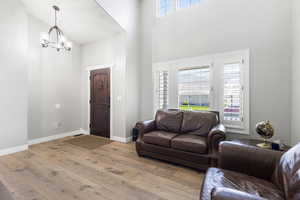 Living room featuring wood-type flooring, a towering ceiling, and a chandelier
