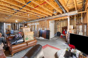 Unfinished basement featuring freestanding refrigerator