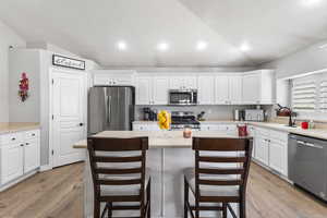 Kitchen featuring appliances with stainless steel finishes, dark wood-style flooring, white cabinetry, recessed lighting, and a kitchen island