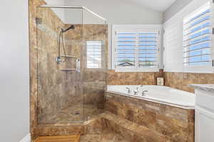 Bathroom featuring a shower stall, a bath, vanity, and vaulted ceiling