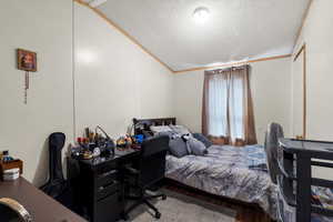 Bedroom with wood finished floors, crown molding, and a textured ceiling