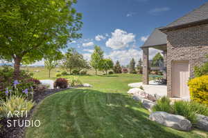 View of grassy yard with a patio area and a balcony