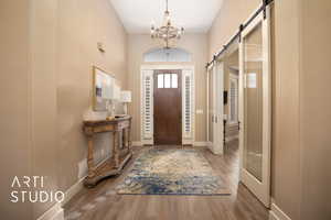 Foyer entrance featuring a barn door, a chandelier, and light wood finished floors
