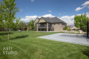 View of basketball court with basketball hoop, a balcony, and a lawn