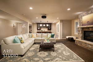 Living room featuring carpet, recessed lighting, a stone fireplace, and bar area