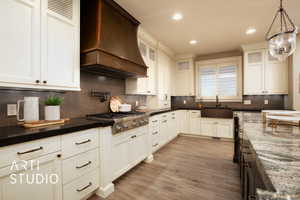 Kitchen featuring backsplash, custom exhaust hood, white cabinetry, and recessed lighting