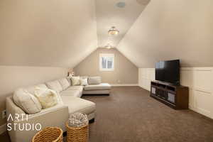 Living area featuring dark carpet, lofted ceiling, and a textured ceiling