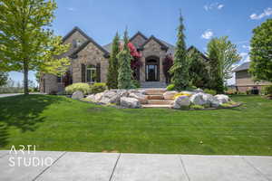 View of front facade with stone siding and a front yard