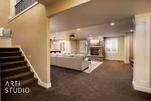 Living area with dark carpet, a stone fireplace, recessed lighting, and stairway