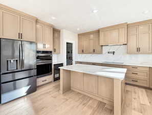 Kitchen with appliances with stainless steel finishes, light brown cabinets, light stone countertops, light wood-style flooring, and recessed lighting