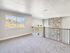 Carpeted empty room with a textured ceiling, recessed lighting, and a mountain view