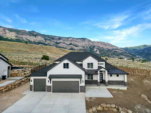 Modern inspired farmhouse with a mountain view, board and batten siding, driveway, stone siding, and roof with shingles