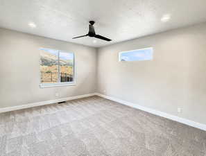 Carpeted spare room with a textured ceiling, plenty of natural light, ceiling fan, and recessed lighting