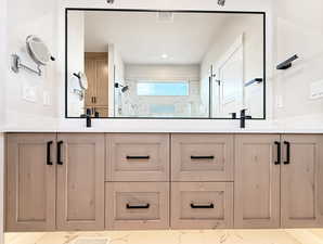 Full bathroom with double vanity, a marble finish shower, and recessed lighting