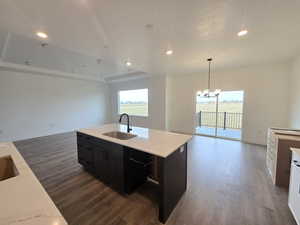 Kitchen with open floor plan, dark cabinets, decorative light fixtures, a raised ceiling, and recessed lighting