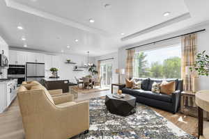 Living area with recessed lighting, light wood finished floors, a textured ceiling, and a tray ceiling