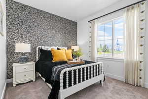 Bedroom with an accent wall, carpet flooring, and wallpapered walls
