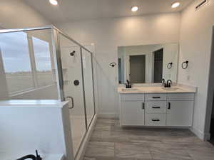 Full bath with double vanity, a stall shower, and recessed lighting
