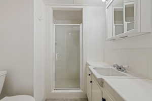 Bathroom with a stall shower, vanity, and decorative backsplash