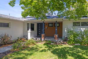 Property entrance featuring a porch, a lawn, and brick siding