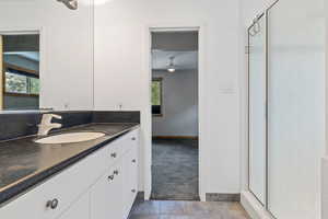 Full bath with a shower stall, vanity, and dark tile patterned floors