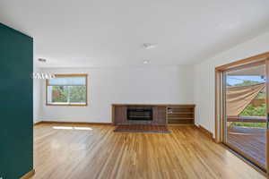Unfurnished living room with a tile fireplace and light wood-style floors