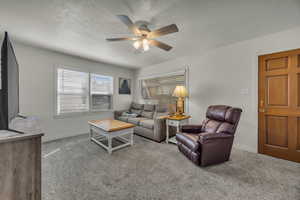 Living area featuring a textured ceiling, light carpet, and a ceiling fan