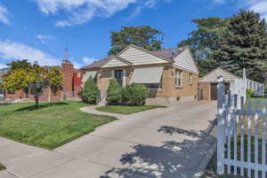 View of front of property with brick siding, an outdoor structure, a garage, and concrete driveway