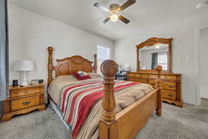 Carpeted bedroom with a ceiling fan and baseboards