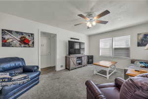 Living area with carpet flooring, a textured ceiling, and a ceiling fan