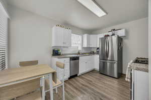 Kitchen featuring stainless steel appliances, white cabinetry, light wood-style floors, and a textured ceiling