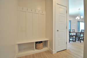 Mudroom featuring light wood-style flooring and a chandelier