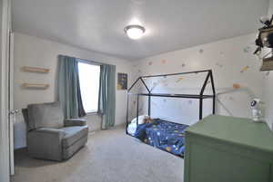 Carpeted bedroom featuring a textured ceiling and baseboards