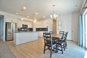 Dining space with light wood-style flooring, recessed lighting, and a chandelier