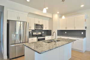Kitchen featuring stainless steel appliances, dark stone countertops, white cabinets, and recessed lighting
