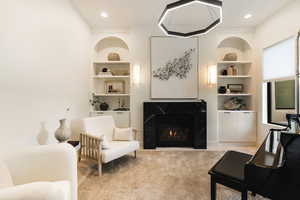 Sitting room with built in shelves, a high end fireplace, carpet, and recessed lighting