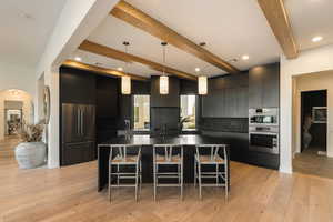 Kitchen with hanging light fixtures, beam ceiling, a large island, stainless steel appliances, and a kitchen breakfast bar
